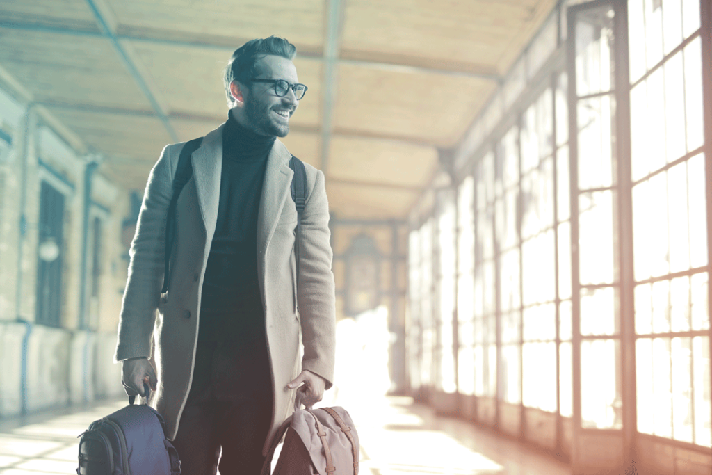 happy business traveler in the airport with luggage in hand