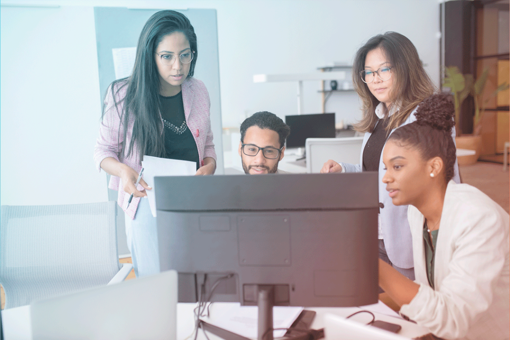 Team members gathered around a computer screen exchanging ideas.