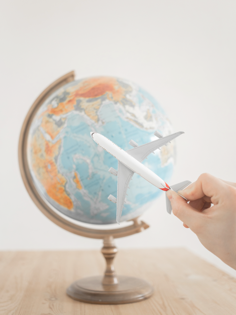 Person holding a plane figurine in front of a globe