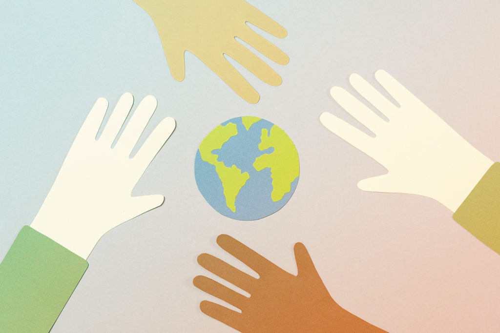 paper cutout of the earth and hands