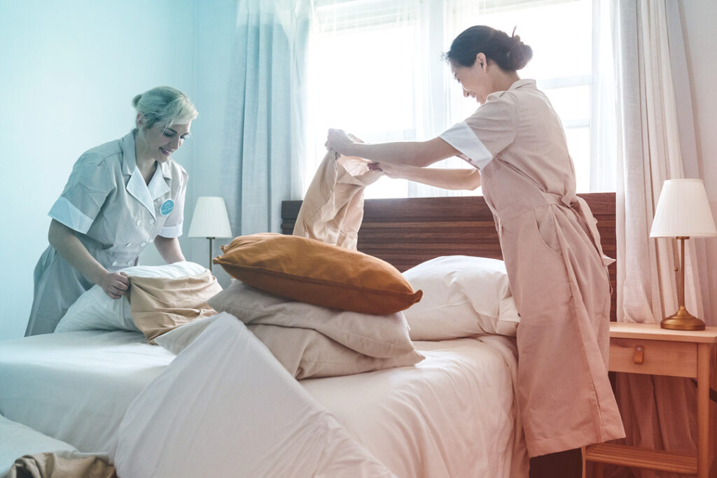 Hotel staff making a bed.