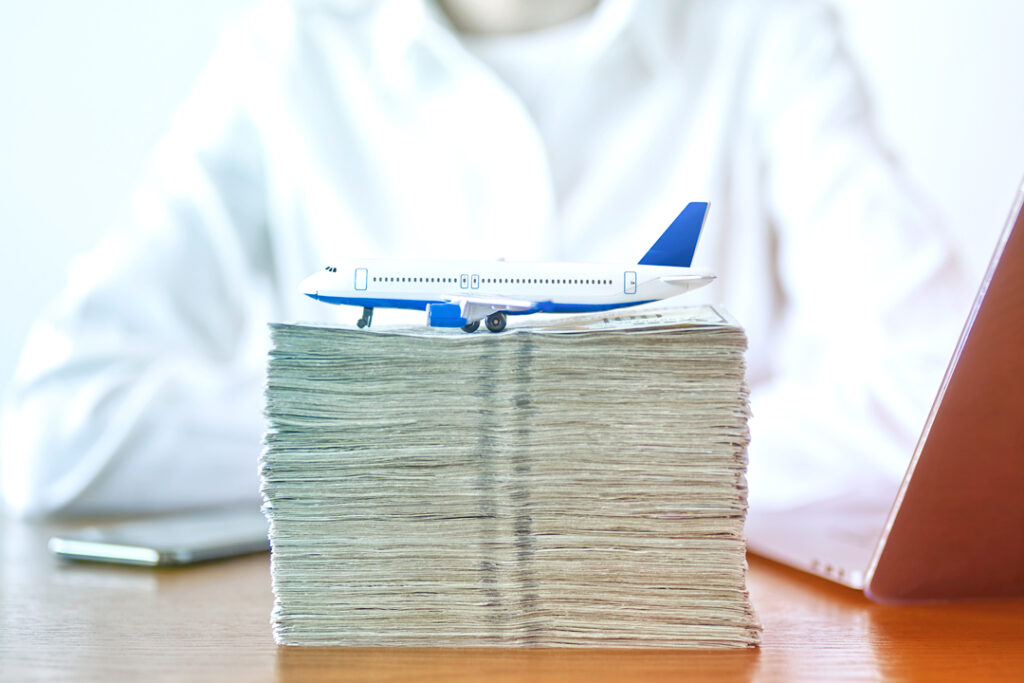 stack of money with toy plane on top