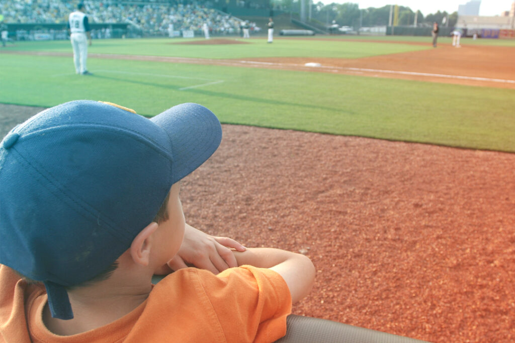 A little boy and a baseball game looking out onto the field