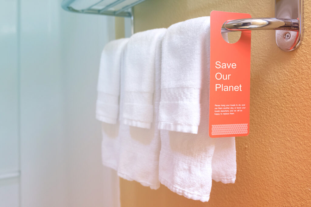 Image of a hotel bathroom. Towels hanging on a bar with a sign that says, save our planet.