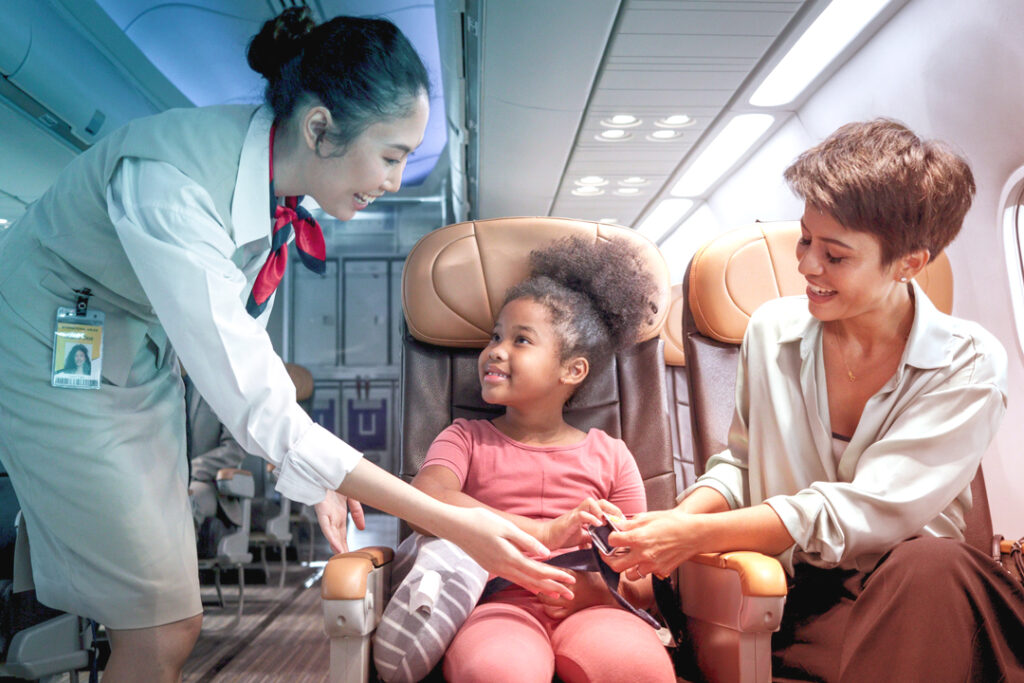 Picture of kind flight attendant, helping a Young passenger on the flight