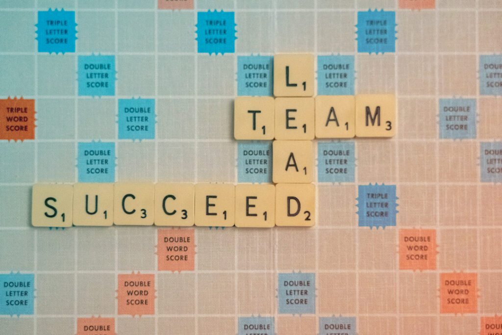 scrabble board with the words Lead Team and Succeed