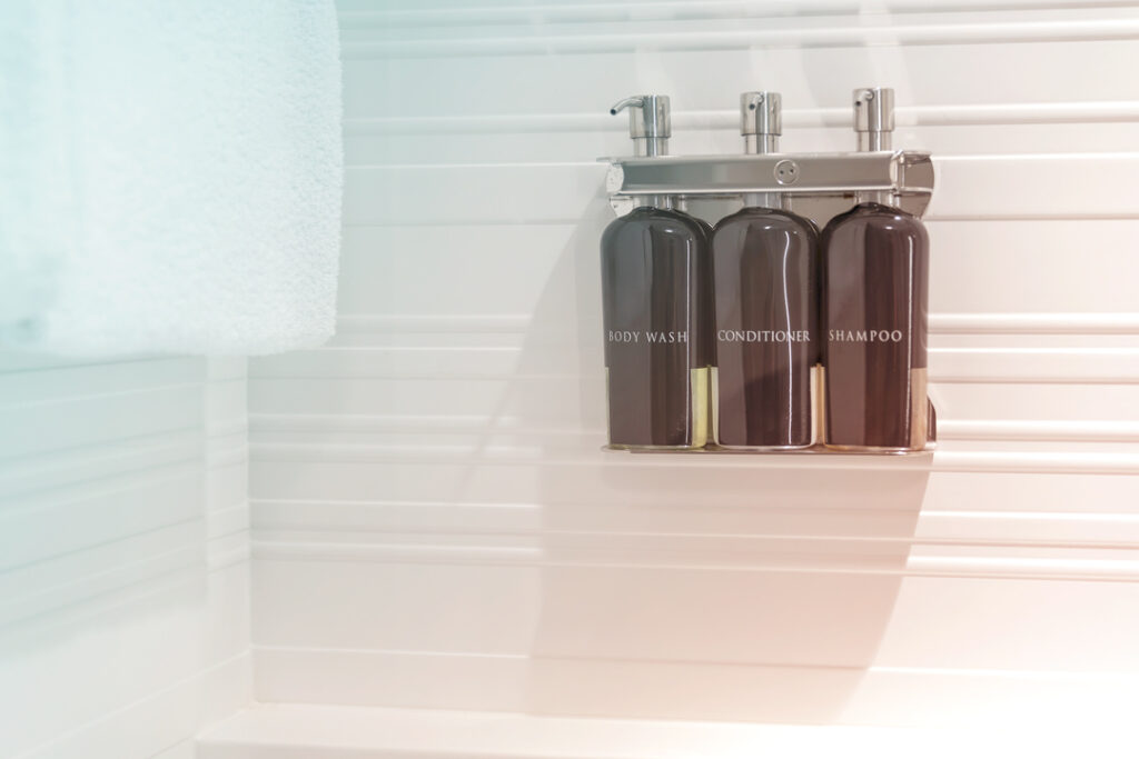 Image of refillable, body wash, conditioner, and shampoo containers in a hotel bathroom - sustainable leadership in hotels