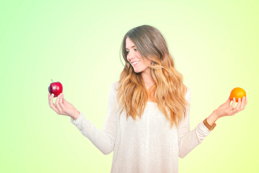 image of a woman holding a apple in one hand and an orang in the other.