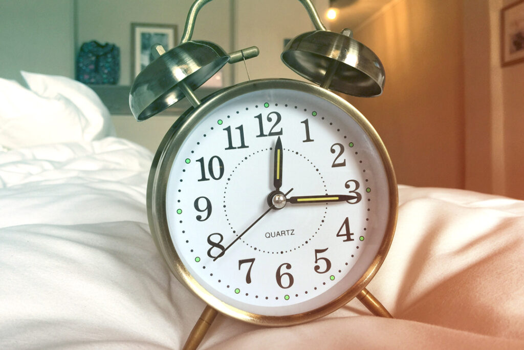 image of a clock on a hotel bed