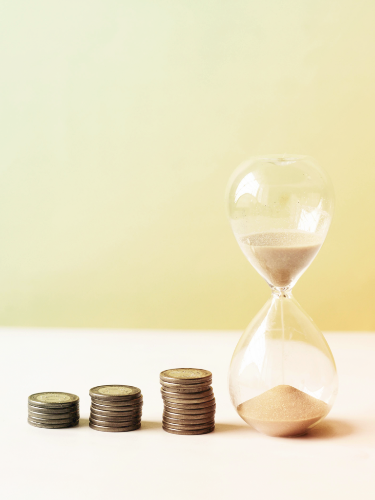 image of stacks of coins and a hourglass - budget for business travel
