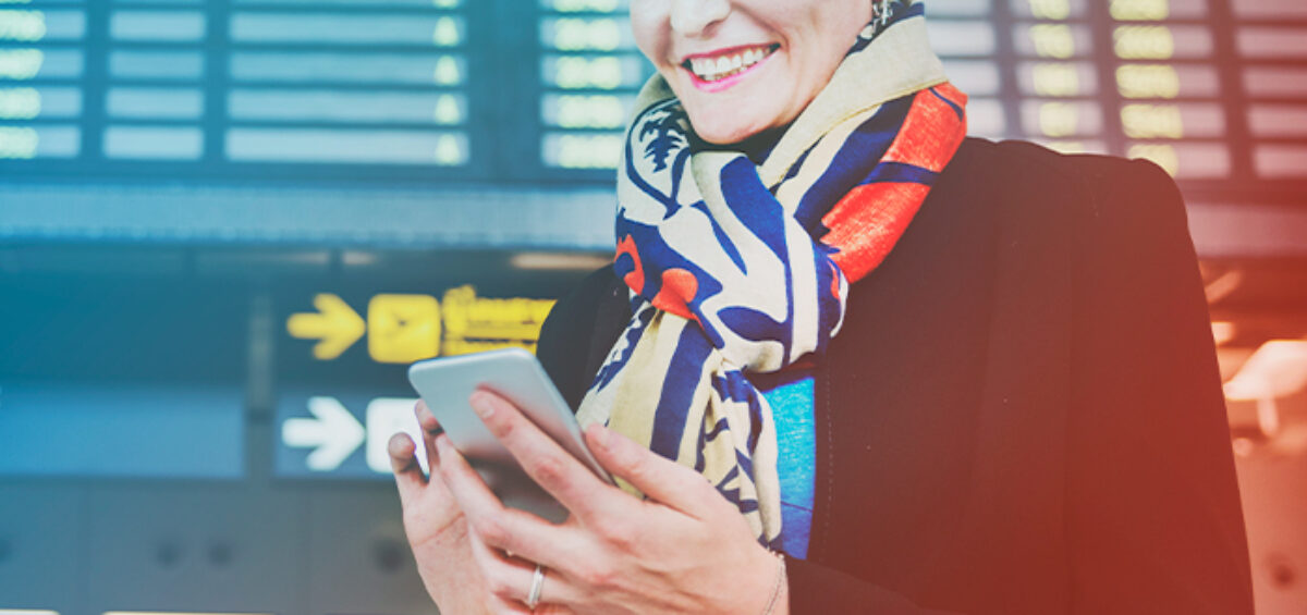 Woman using a Modern Business Travel Booking Tool on her phone at the airport
