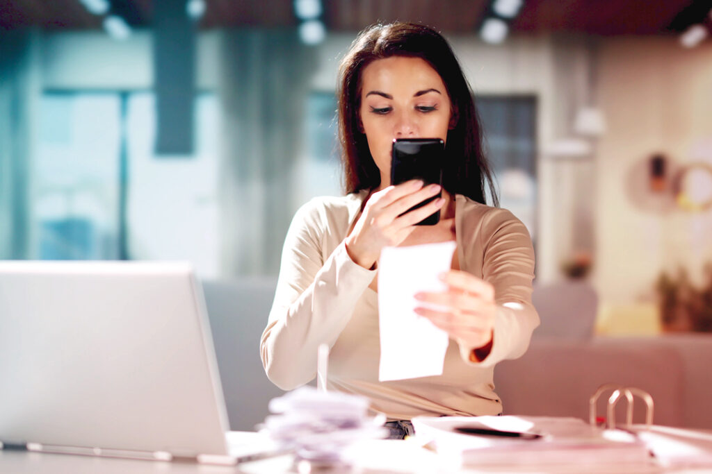 Image of a traveler, taking a picture, or scanning a receipt from their travel expenses.