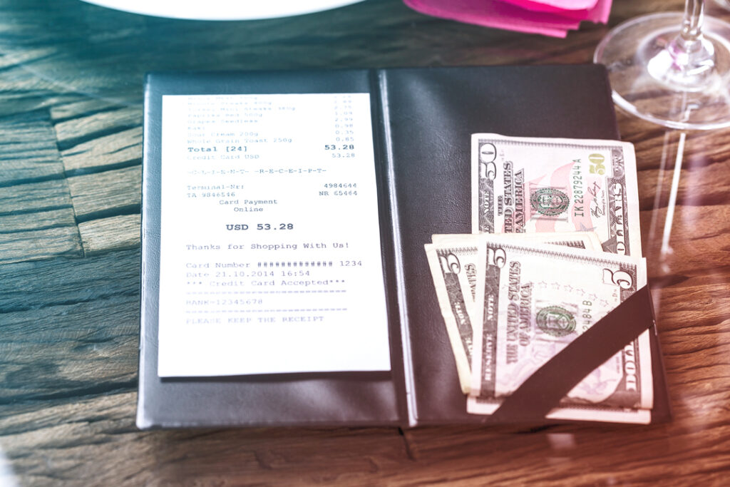 Image of restaurant check and cash to pay it.
