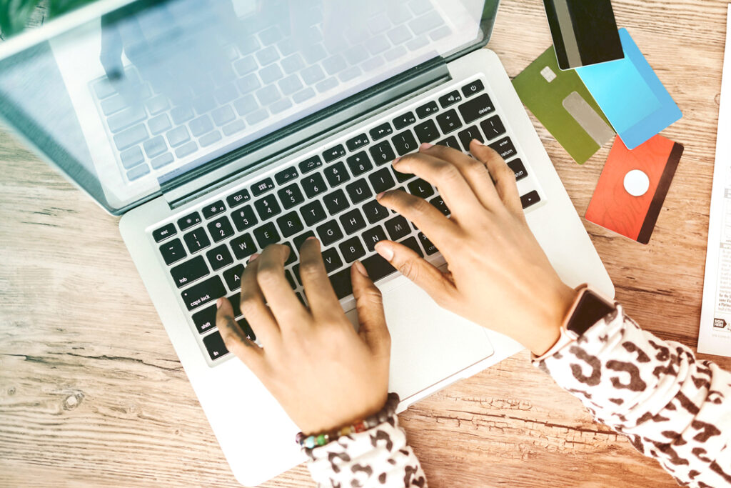 Image of a business person working on their computer booking a fliggt with their creadit card on their desk.
