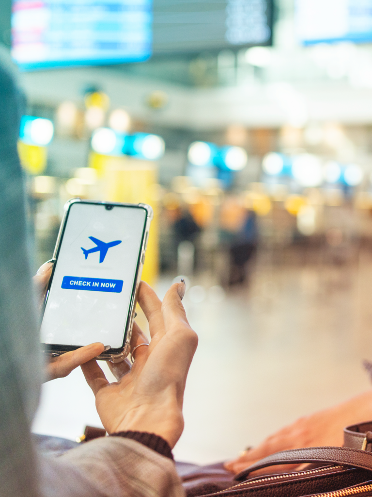 Image of a Traveler in the ariport using a AI app on thier phone to maximize ai use.