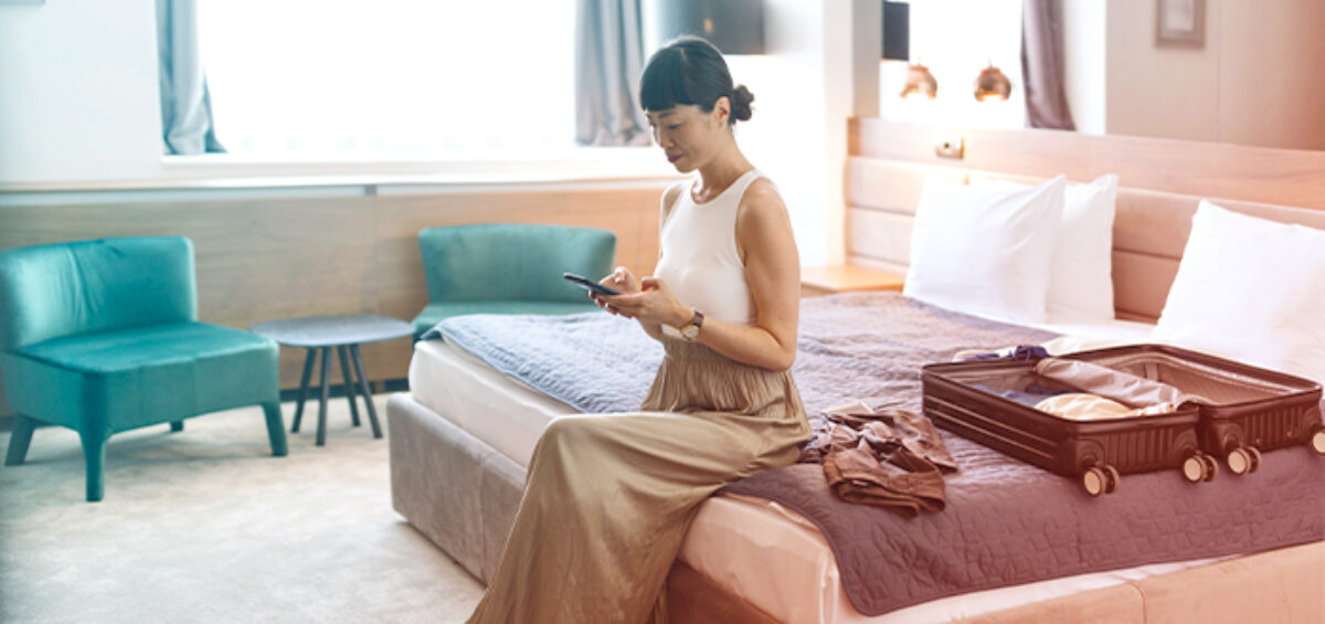 A woman sitting in a hotel room preparing for her long return flight with a lightly packed suitcase