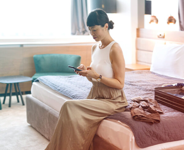 A woman sitting in a hotel room preparing for her long return flight with a lightly packed suitcase