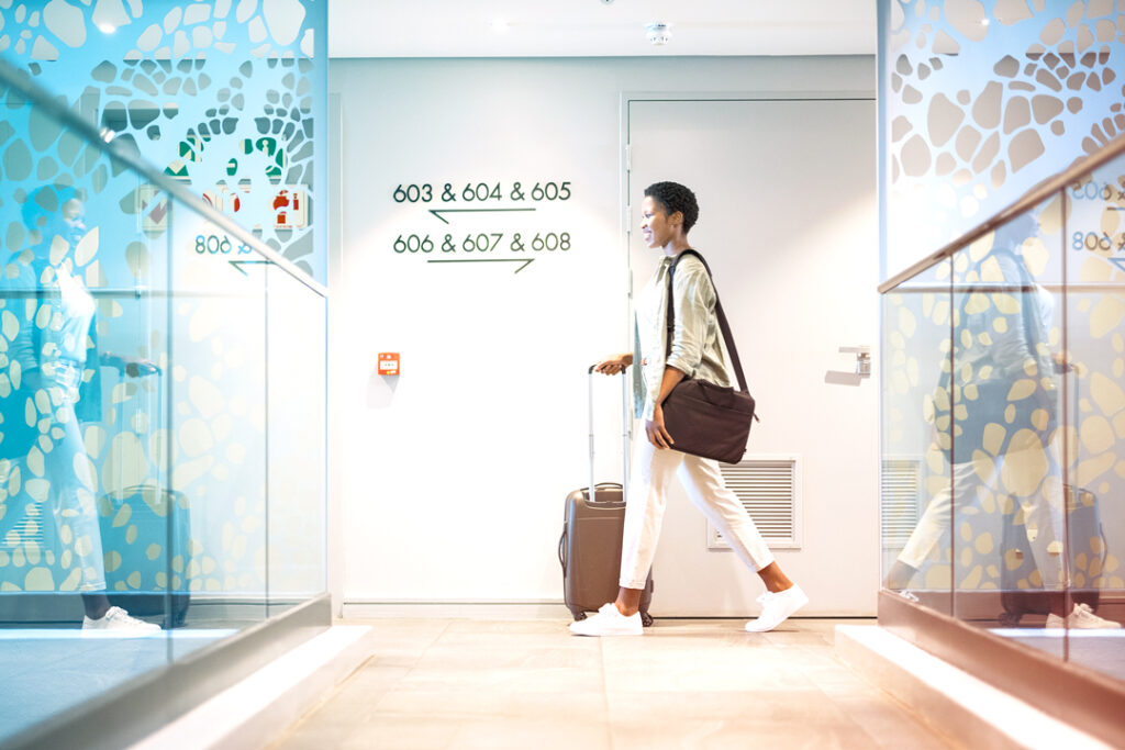 Image of a Traveler walking to their room ina hotel. Sustainable corporate travel policies in 2025