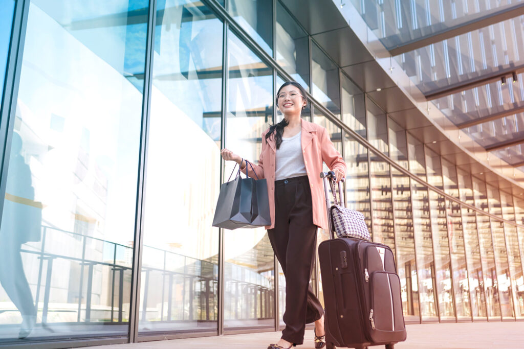 Image of a business traveler, with their suitcase and shopping bags at the airport