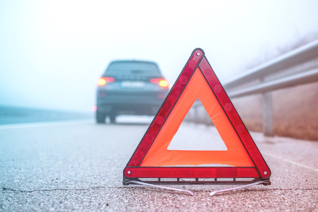 Image of car pulled over on the side of the road with caution signage