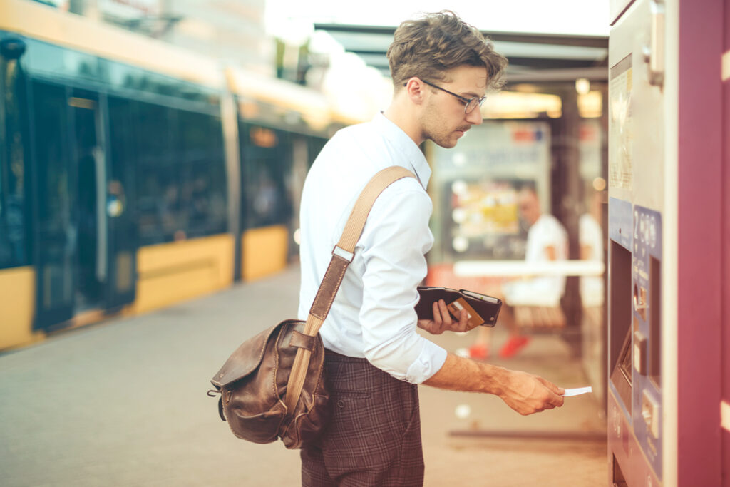 Image of a traveler, purchasing a train ticket at station kiosk