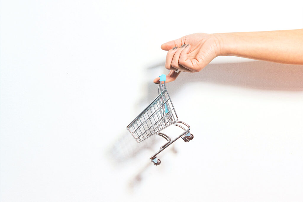 Image of a hand holding a miniature toy shopping cart representing self-service corporate travel tools