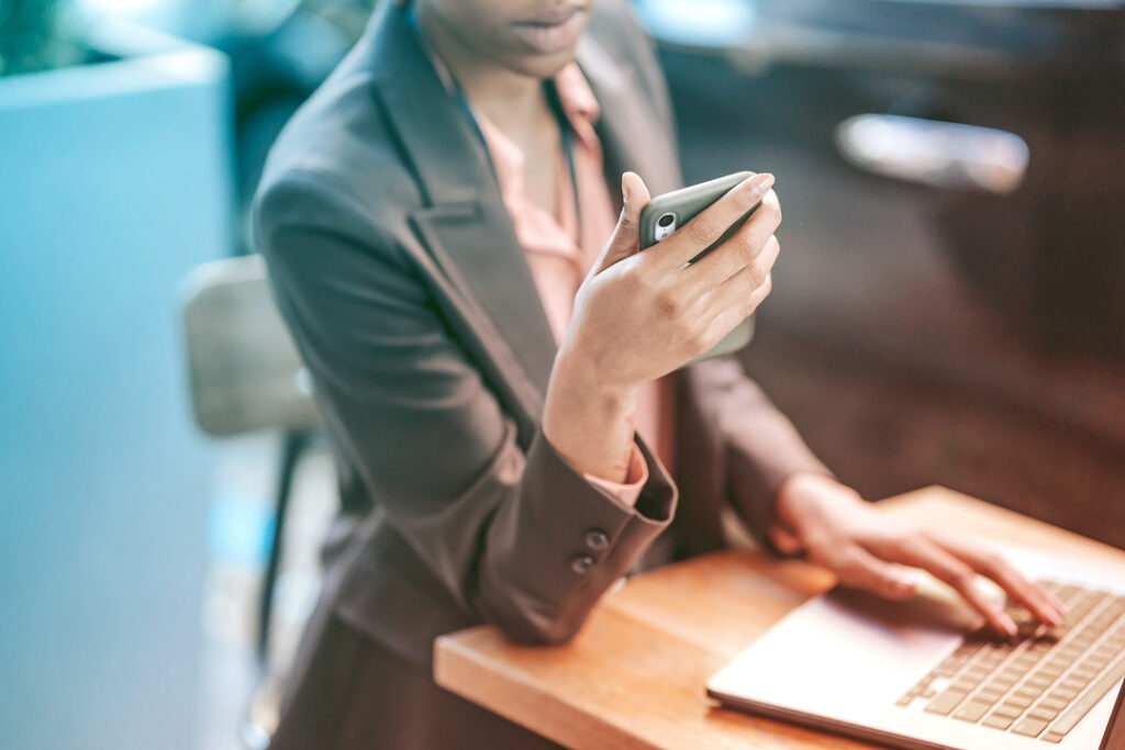 traveler managing client relationships while on their phone and laptop in a cafe setting