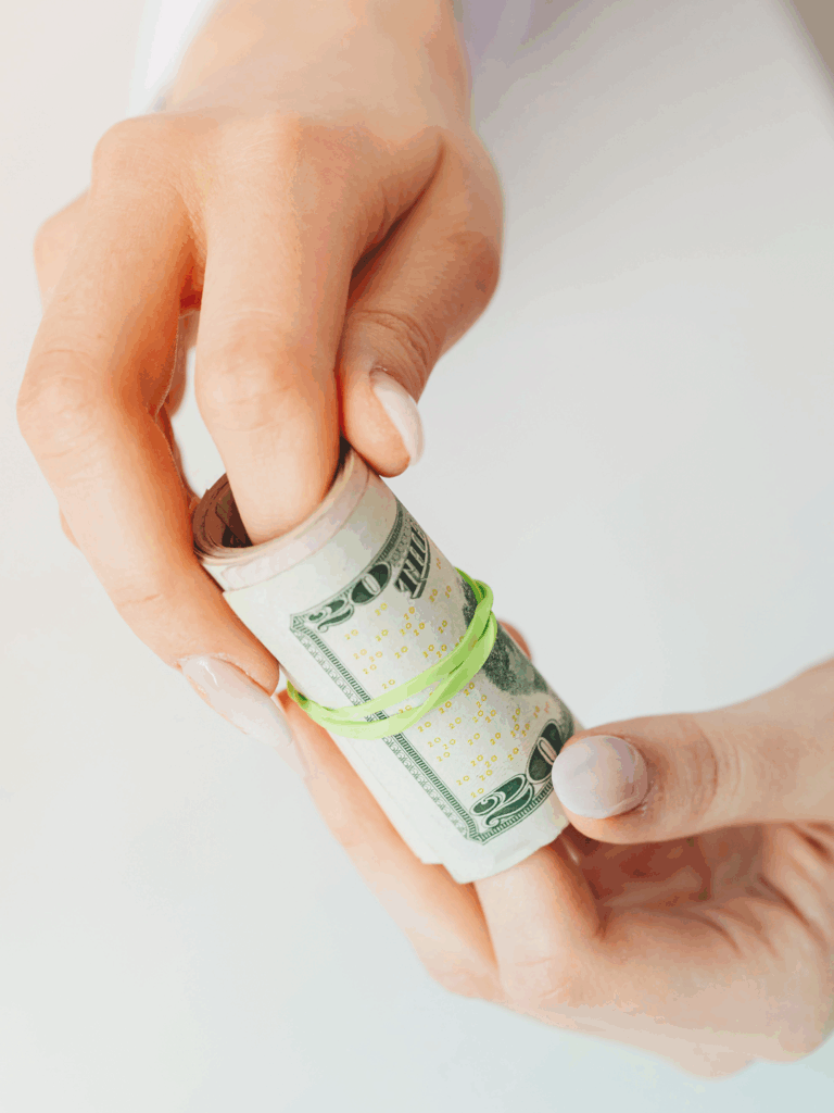 Hands holding a roll of money - savings from split ticketing