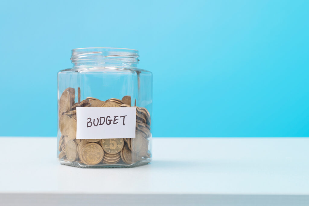 Glass jar that contains coint with a label that says "BUDGET"