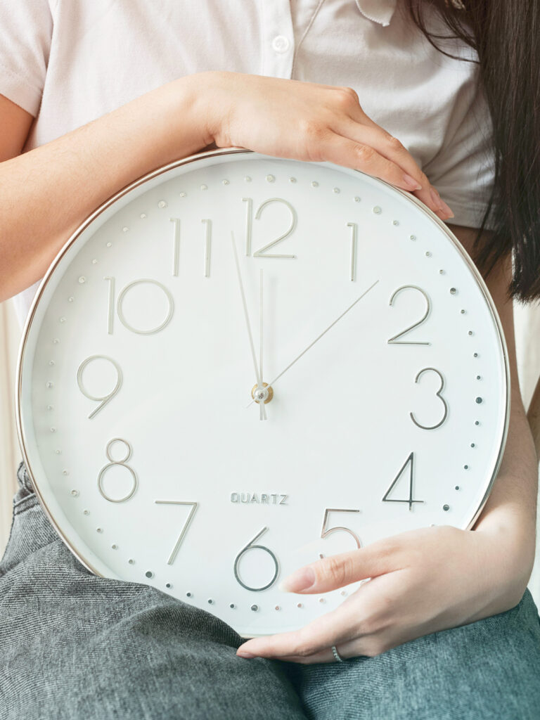 Woman holding a large clock representing the right time to have corporate travel supplier negotiations