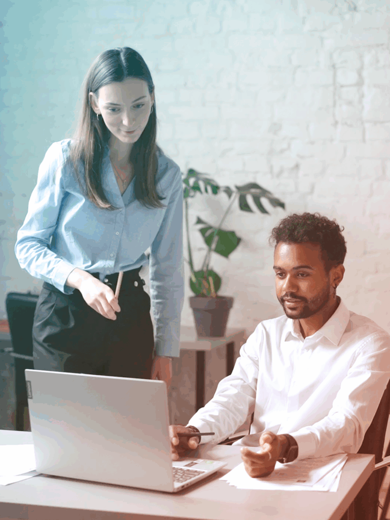 Two business professionals are having a discussion around a computer.