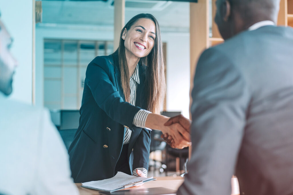 Two business travel airline sourcing professionals shaking hands and smiling
