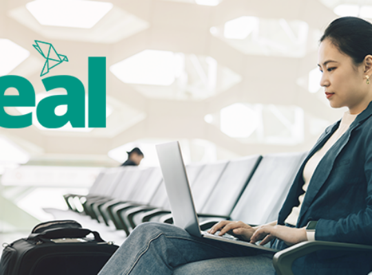 woman at the airport on a laptop with the Teal product logo
