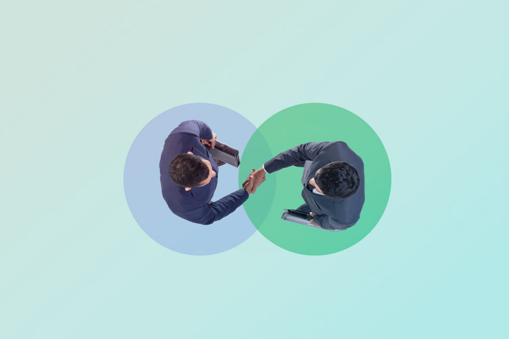 Two businessmen shaking hands with a vendiagram behind them.
