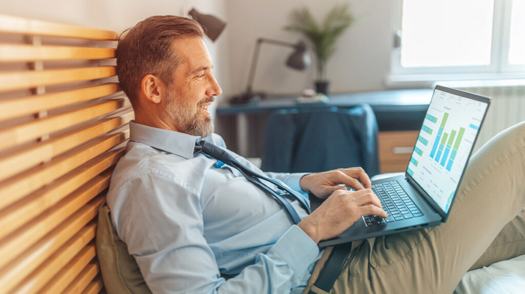 A Traveler working from their hotel room reviewing managed travel benefits data. 
