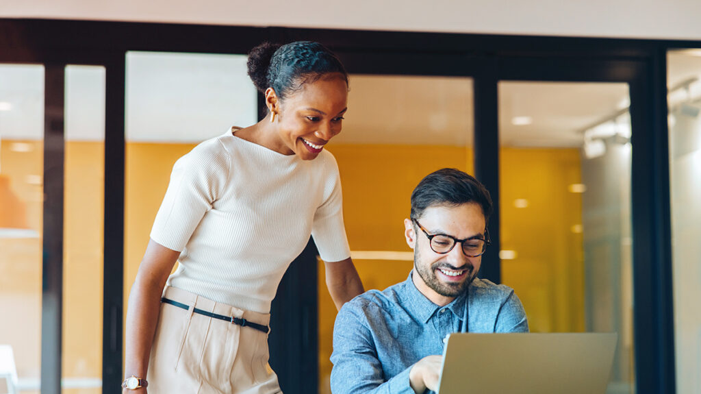 Travel Manager and Executive looking at data a computer smiling