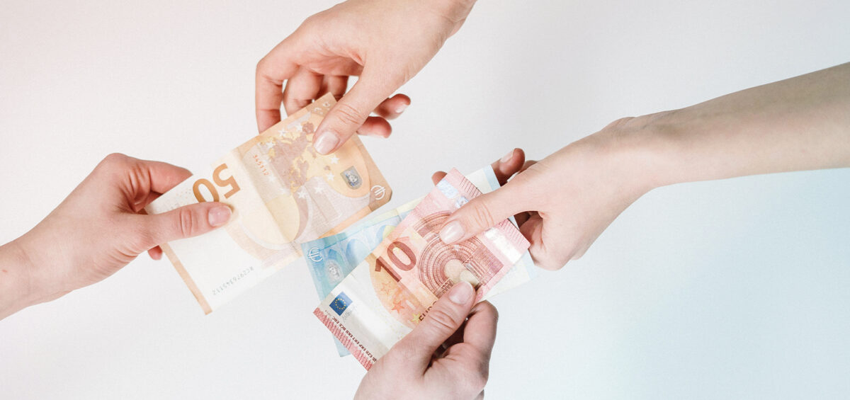 Two hands passing money, representing Business travel price discrepancies inside and outside a booking tool
