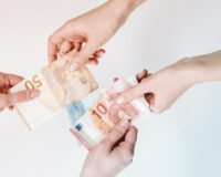 Two hands passing money, representing Business travel price discrepancies inside and outside a booking tool