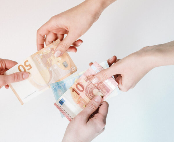 Two hands passing money, representing Business travel price discrepancies inside and outside a booking tool