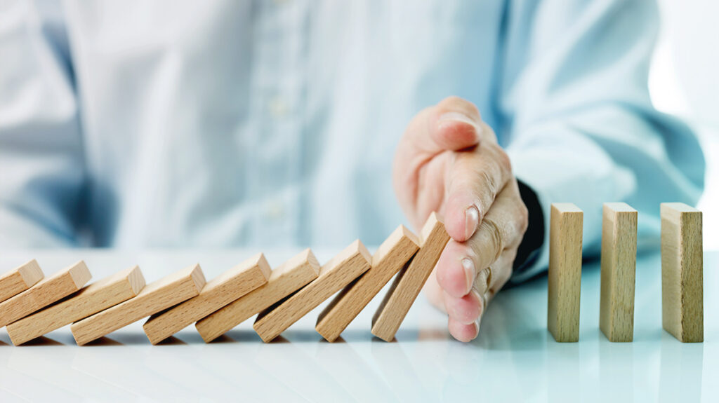 A hand stopping the fall of dominoes representing AI governance and accountability